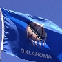 Die Flagge zeigt auf blauem Untergrund einen indianischen Büffellederschild mit sieben herabhängenden Adlerfedern hinter einer Friedenspfeife und einem Olivenzweig. Die Friedenspfeife und der Olivenzweig symbolisieren das friedliche Zusammenleben zwischen den ansässigen nordamerikanischen Indianern und den zugewanderten Europäern.<br /><br />Die Farbe Blau erinnert an die Uniformen der indianischen Choctaw-Soldaten während des Sezessionskriegs. Die indianischen Friedenssymbole erinnern an den früheren Namen „Indian Territory" .<br />Jede Menge indianische Zeichen incl. einer Friedenspfeife.<br />Wenn man erstmal alle unterdrückt oder ausgerottet kann man gut so tun als ob man sich für die indianische Kultur interessiert.....